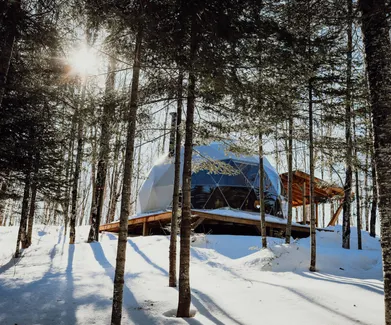 white geodesic dome on wooden deck in snowy forest