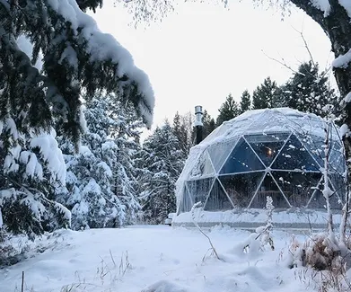 white geodesic dome with stack in winter in forest