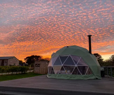 green geodesic dome with a sunset view