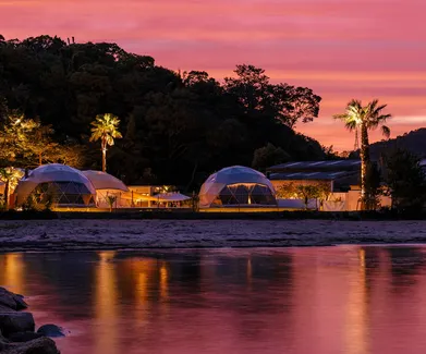 white geodesic domes with stack on the beach in sunset