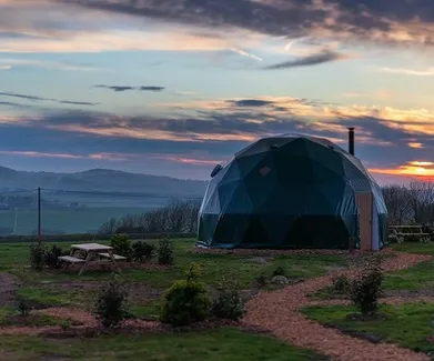 green geodesic dome infield in sunset