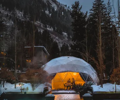 a white geodesic dome in winter, In the foreground, the illuminated swimming pool