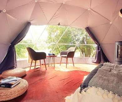 interior of geodesic dome with view at window, coffee table, chairs and fireplace