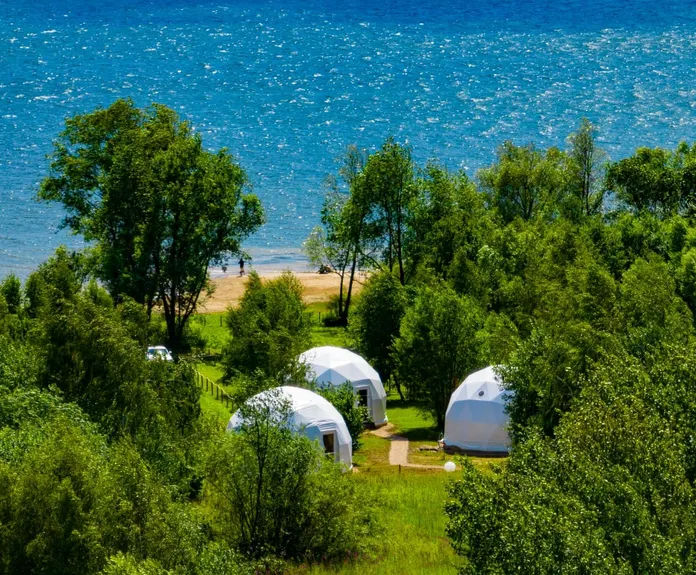 three white geodesic dome on the field beside of sea