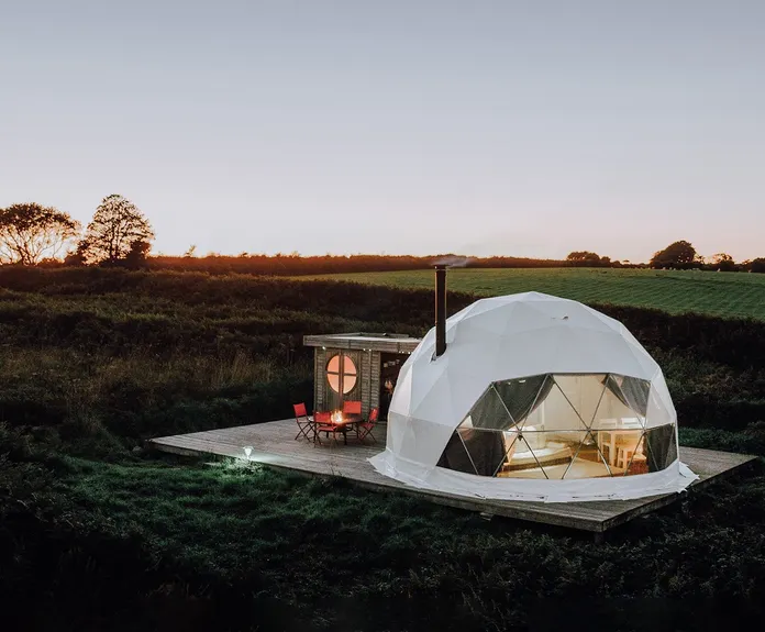 white geodesic dome with stack on the field in sunset