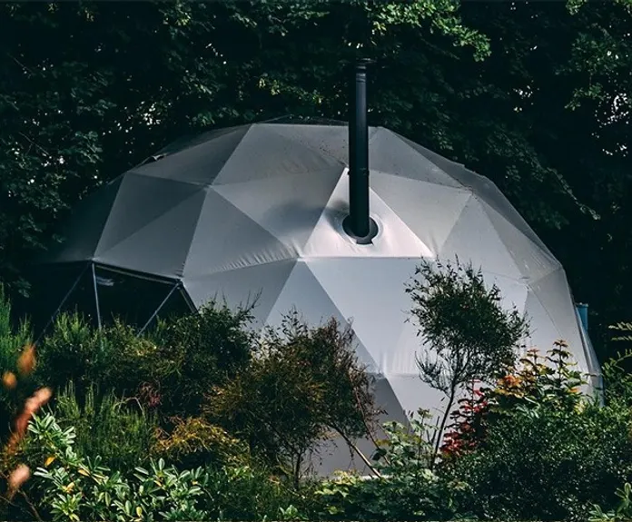 grey glamping geodesic dome in the middle of woods