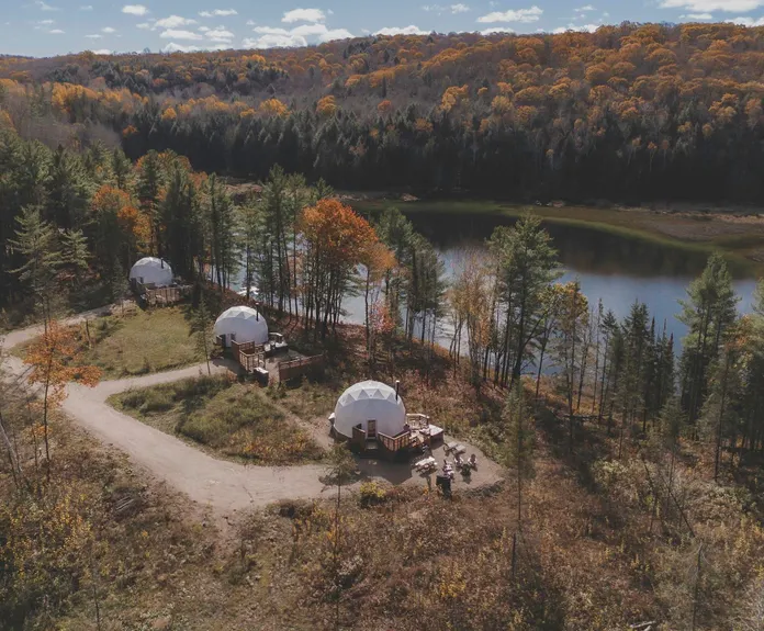 white geodesic domes in the forest, near lake, autumn