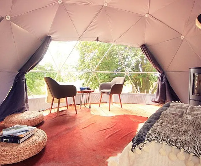 interior of geodesic dome with view at window, coffee table, chairs and fireplace