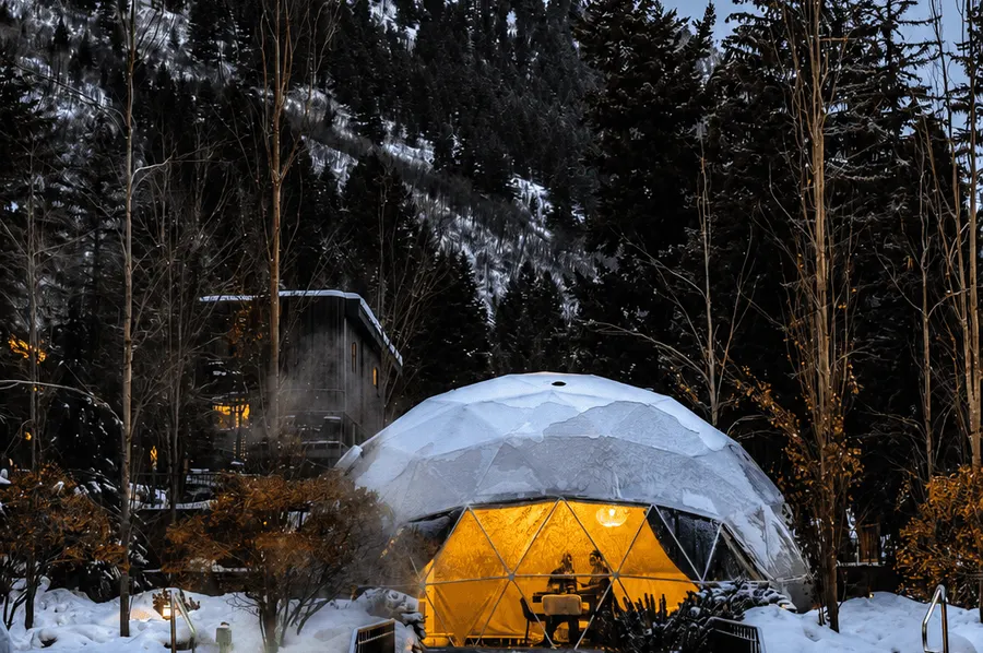 a white geodesic dome in winter, In the foreground, the illuminated swimming pool