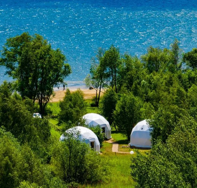 three white geodesic dome on the field beside of sea