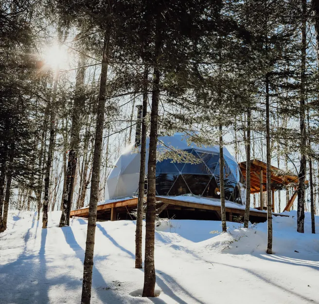 white geodesic dome on wooden deck in snowy forest