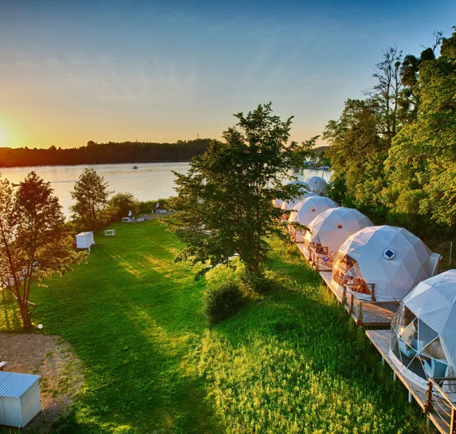 white geodesic domes on the lake shore during sunset