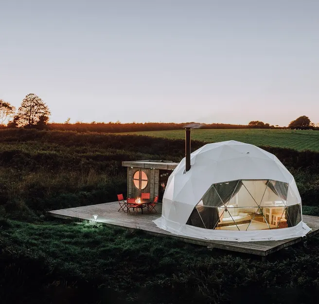 white geodesic dome with stack on the field in sunset