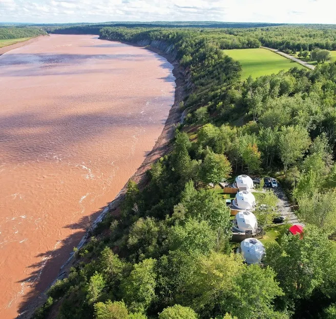 four white geodesic domes near the river during the day