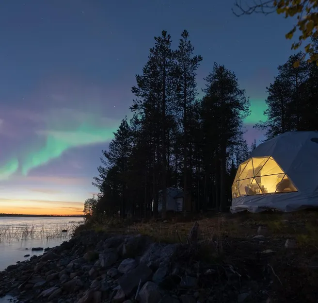 White geodesic dome on a hillside overlooking the aurora borealis
