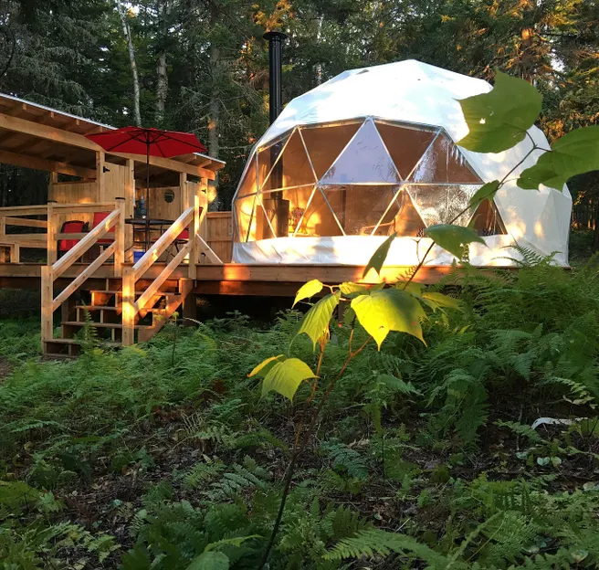 white geodesic dome on wooden deck near forest