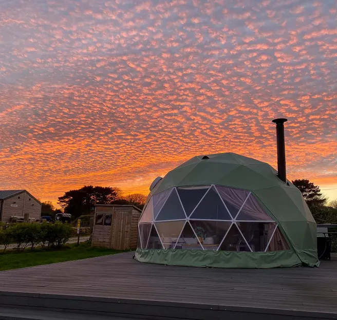 green geodesic dome with a sunset view
