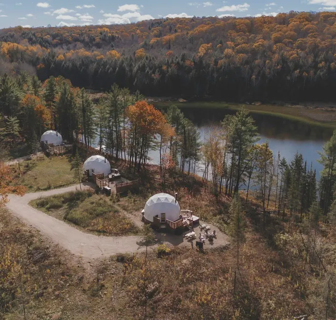 white geodesic domes in the forest, near lake, autumn