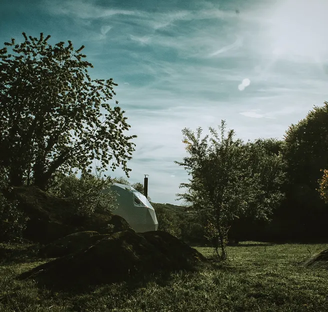 white geodesic dome on the field with some trees