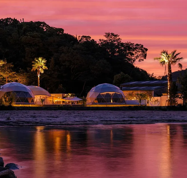 white geodesic domes with stack on the beach in sunset