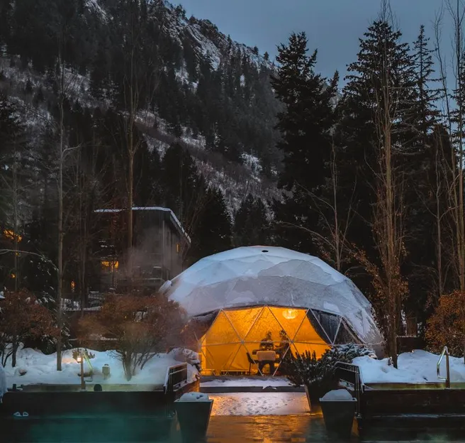 a white geodesic dome in winter, In the foreground, the illuminated swimming pool