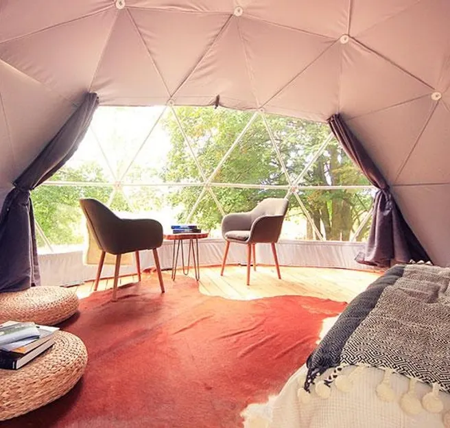 interior of geodesic dome with view at window, coffee table, chairs and fireplace