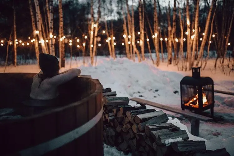 woman in sauna in winter with view of fireplace and trees