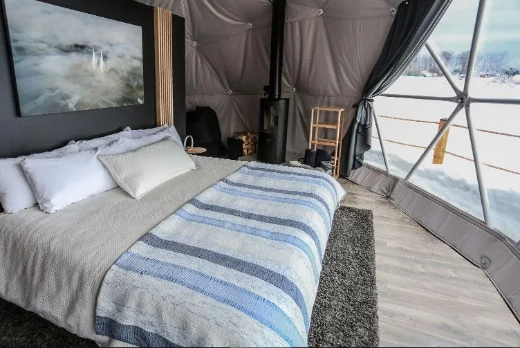 interior of a geodesic dome with a view of the bed, window and stove