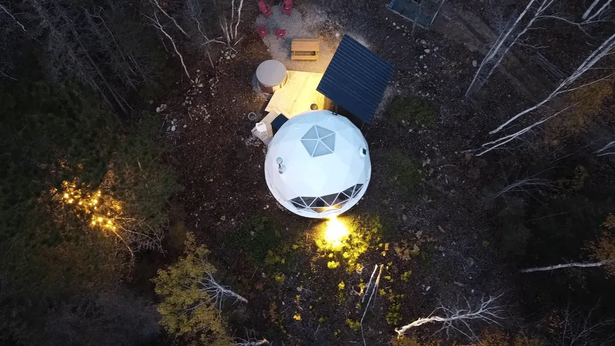 drove view of white geodesic dome in the forest