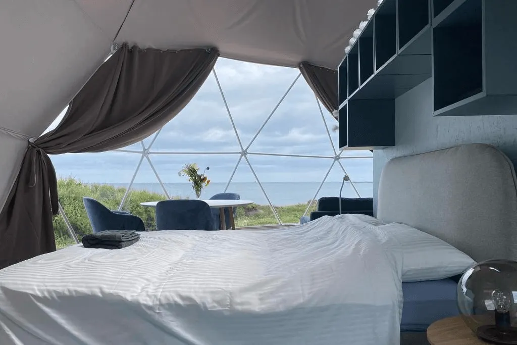 inside of geodesic dome with a bed, some cabinets and a window