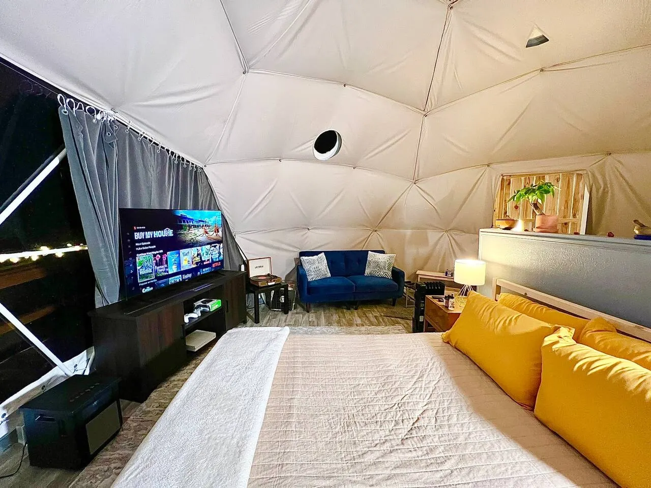 interior of a geodesic dome with a view of the bed, tv and window during the night