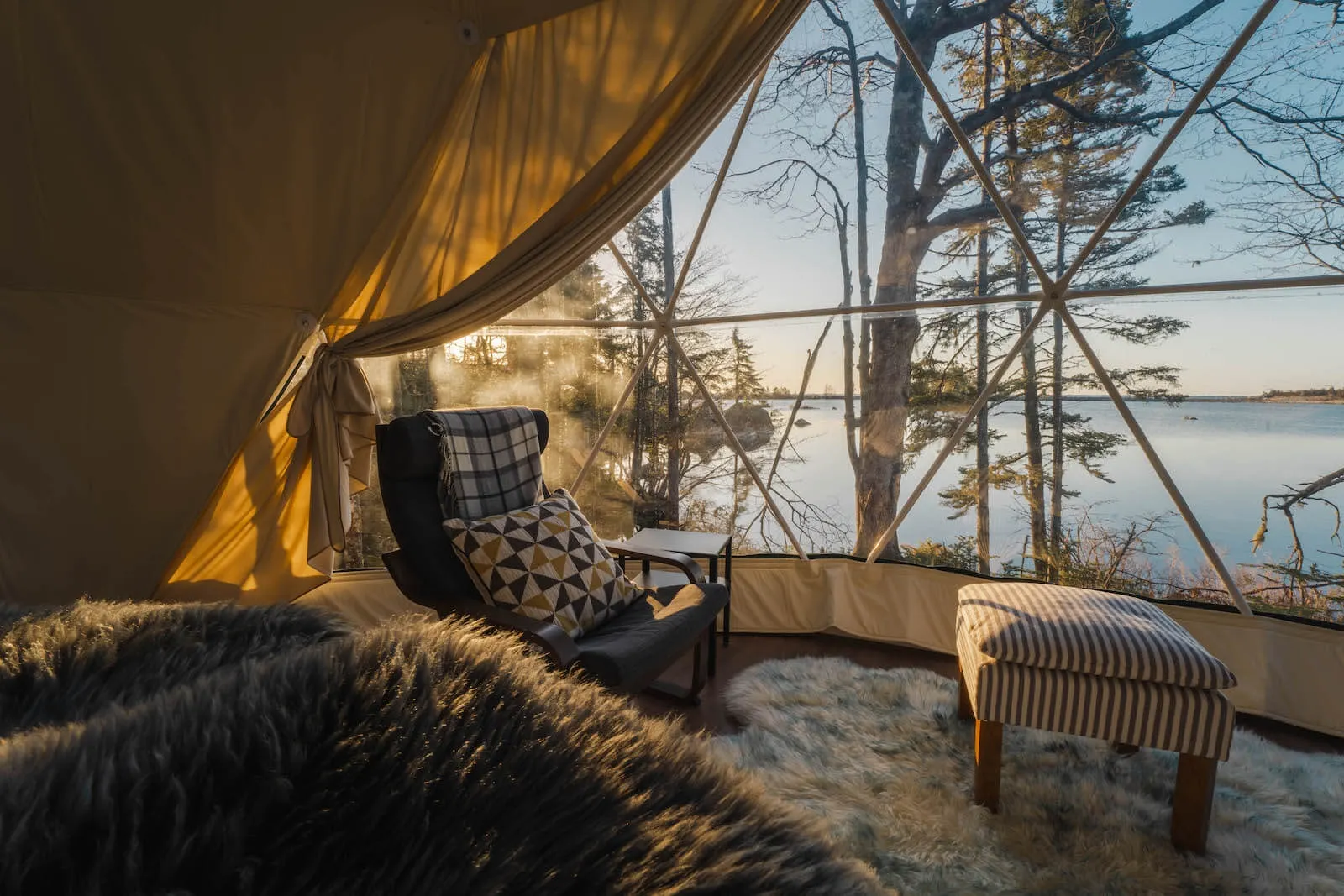 inside of geodesic dome with a bed, an armchair and a rug