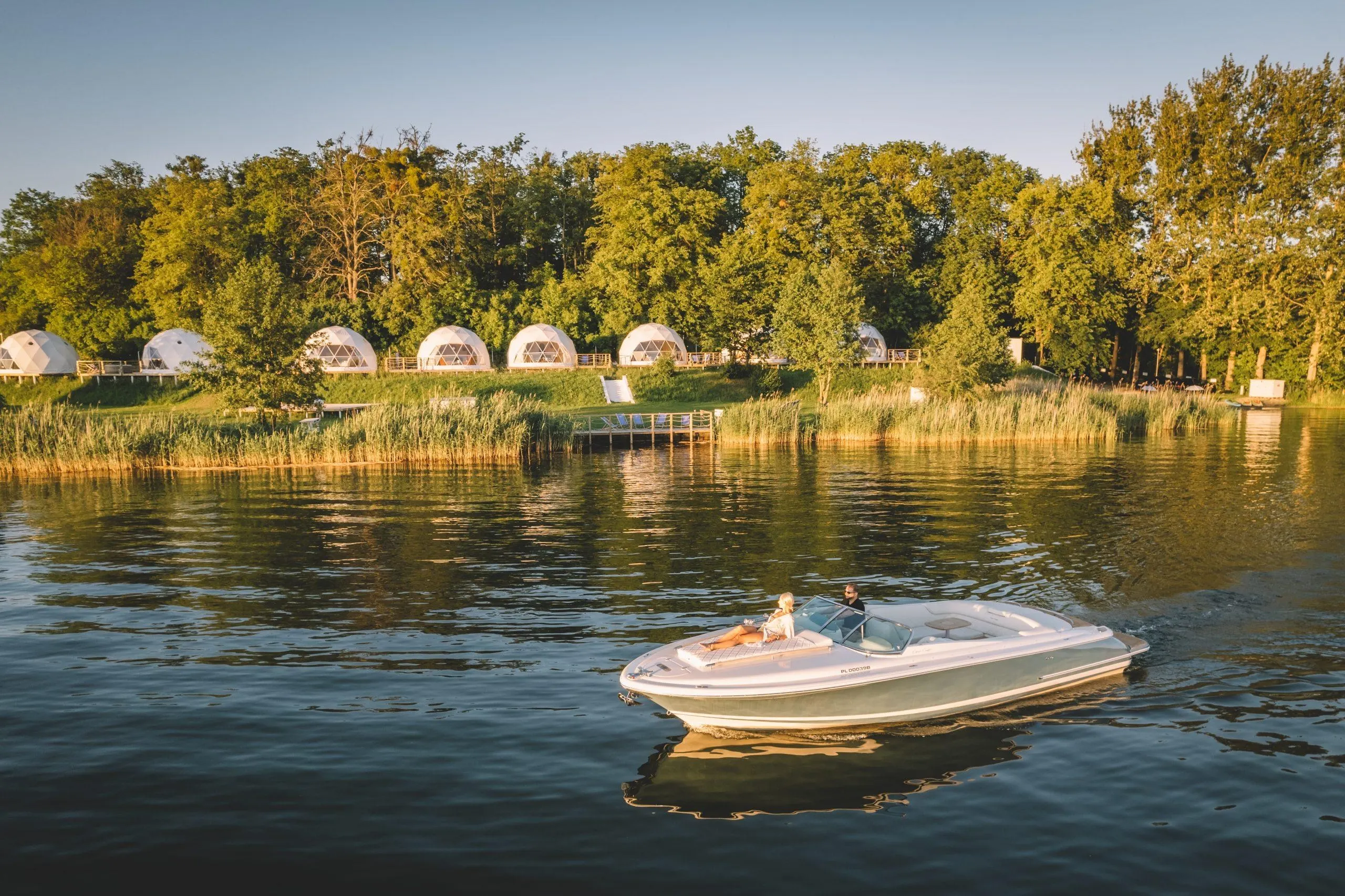 a woman and a man on a boat, white geodesic domes in the background