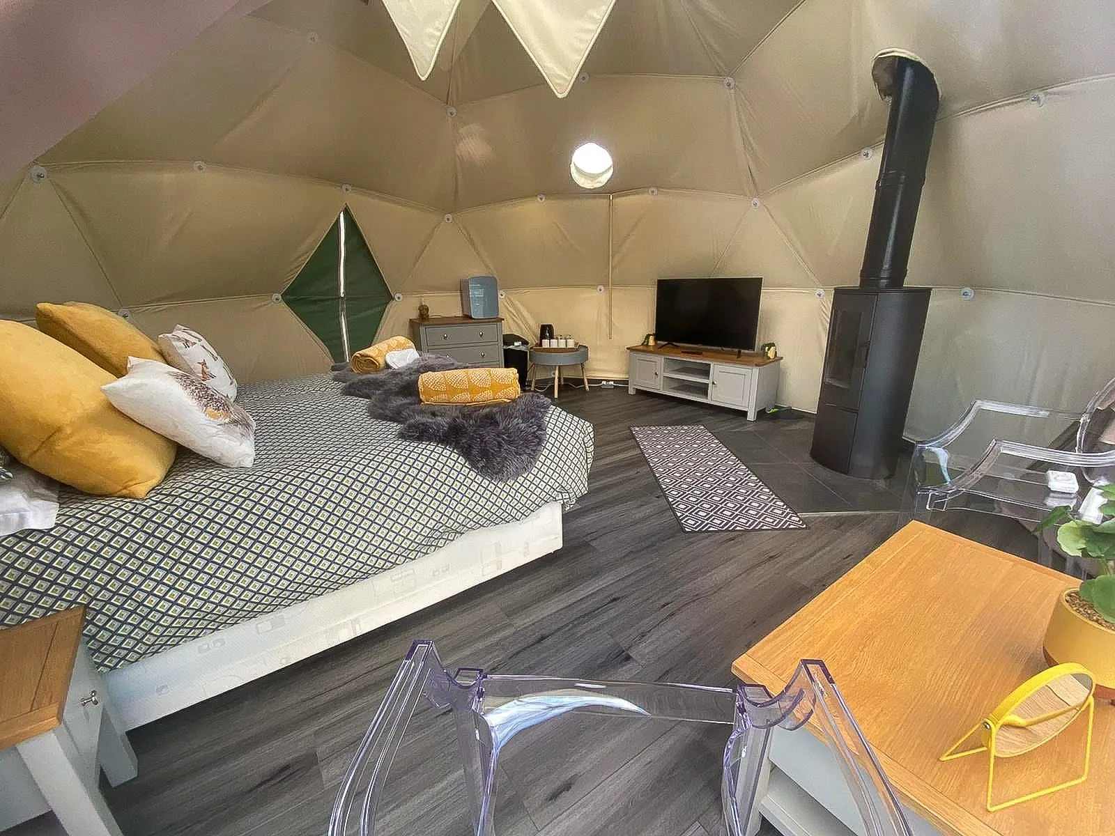 inside of geodesic dome with a stove, a bed, some chairs and a tv