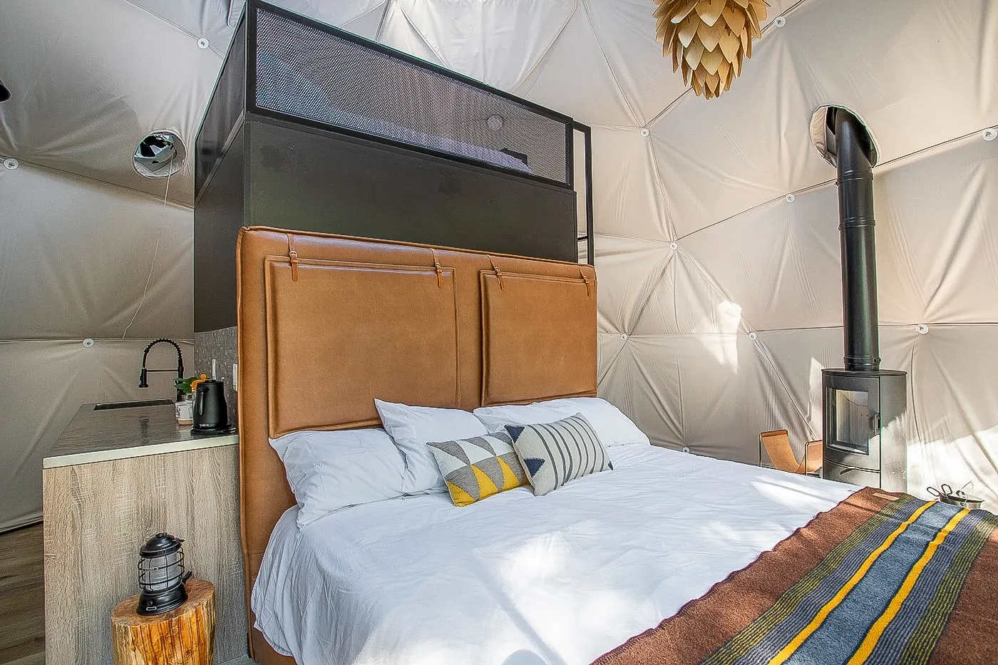 inside of the geodesic with a bed, a stove and a kitchenette