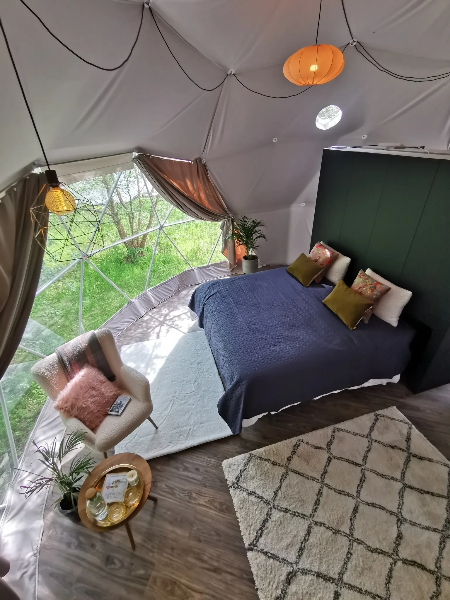 inside of geodesic dome with a bed, an armchair and rugs