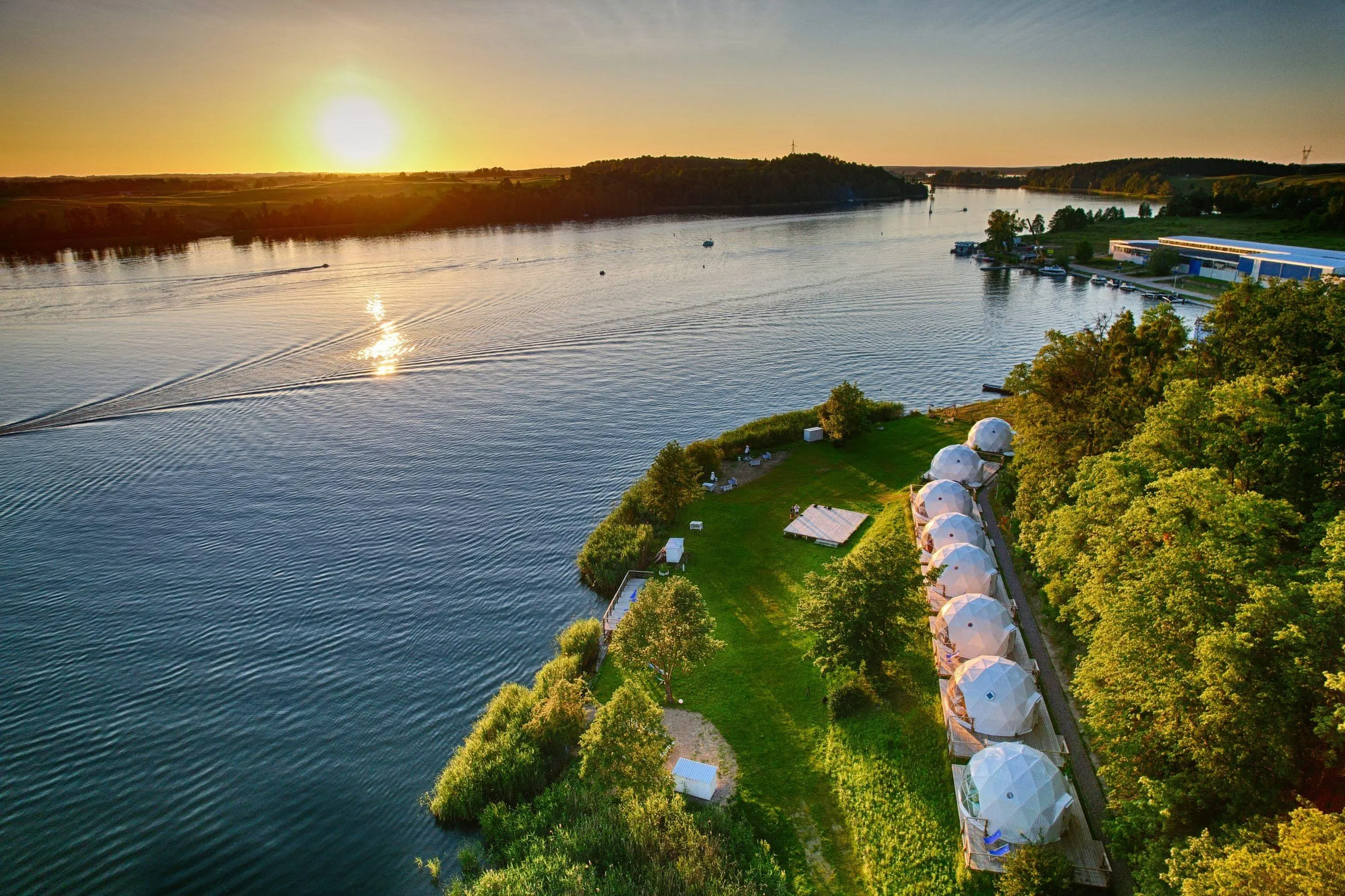 white geodesic domes on the shore of the lake during sunset