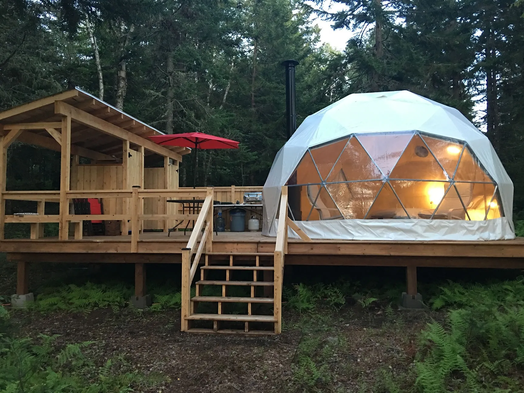 white geodesic dome on wooden deck near forest