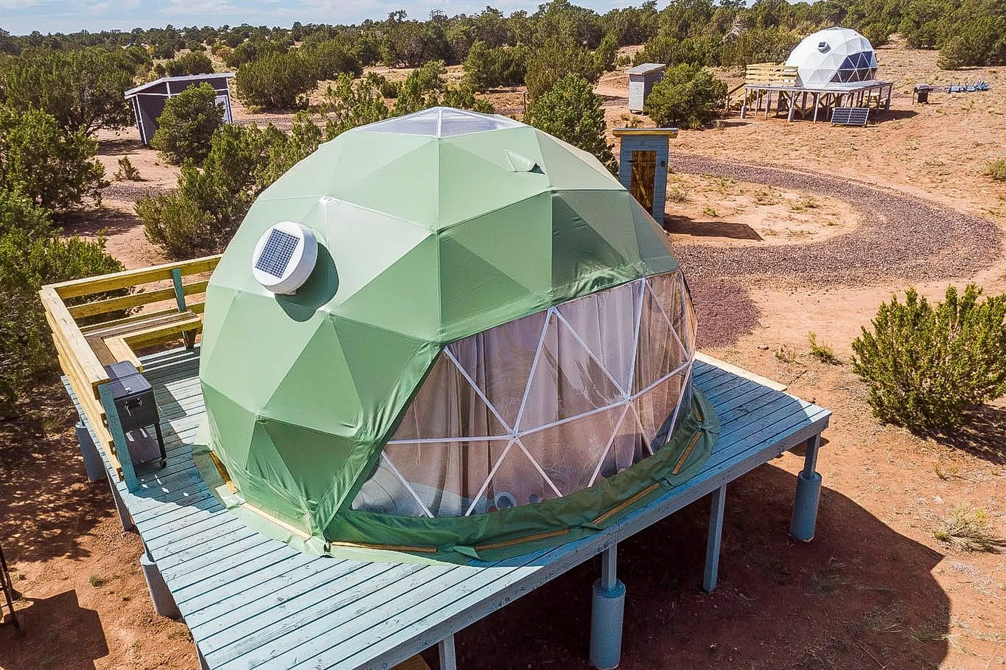 green geodesic dome on wooden deck and white geodesic dome on wooden deck