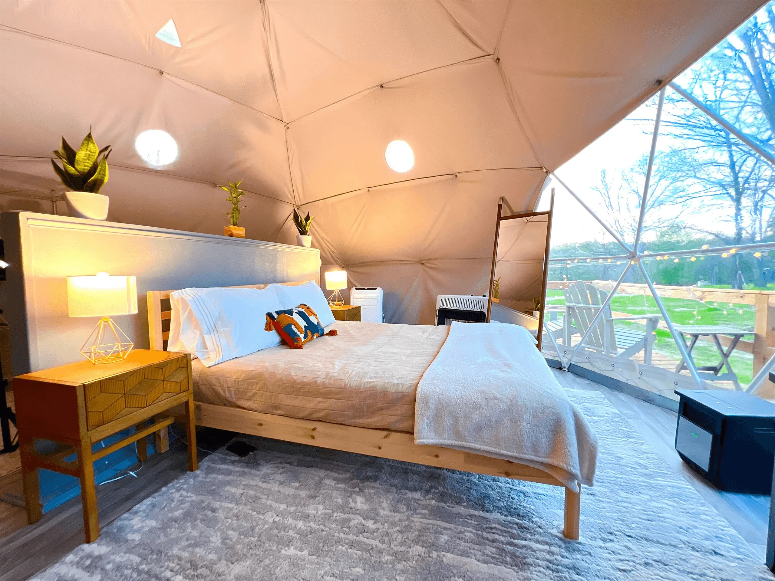 interior of a geodesic dome with a view of the bed and window during the day
