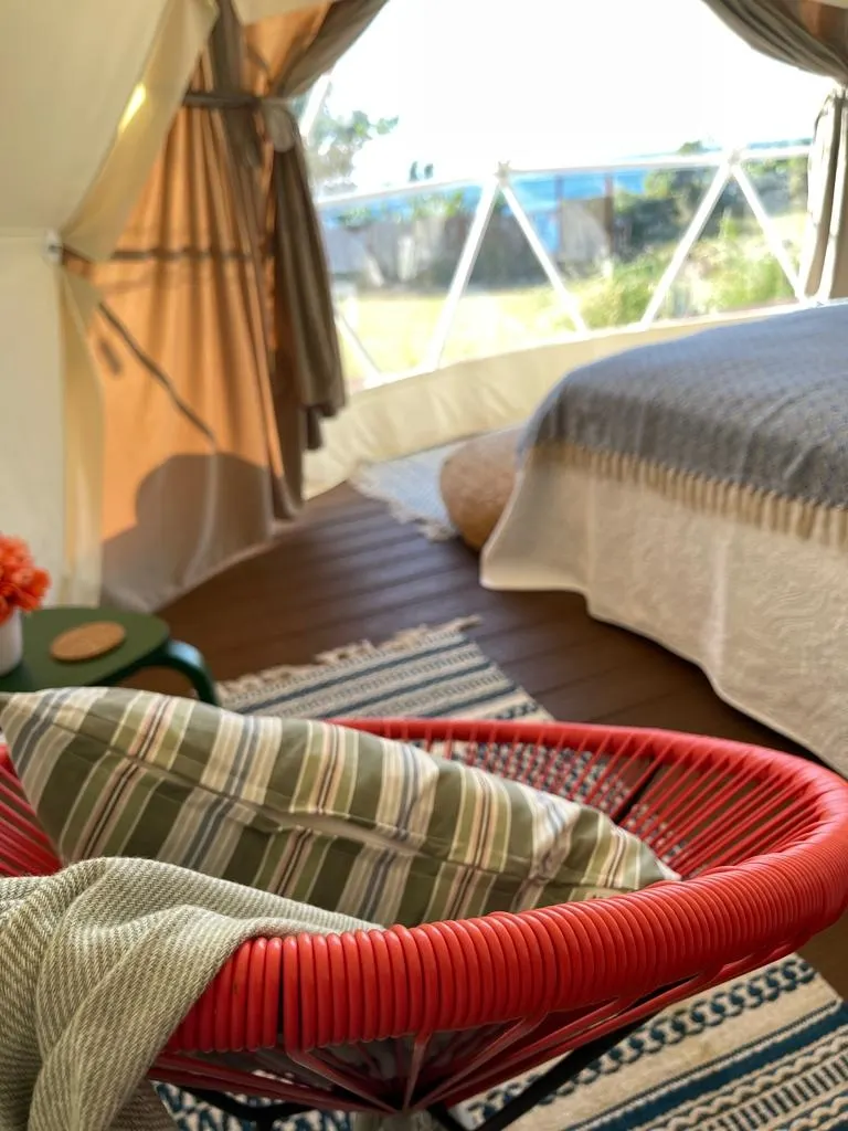 inside of geodesic dome with a chair, a bed and a window