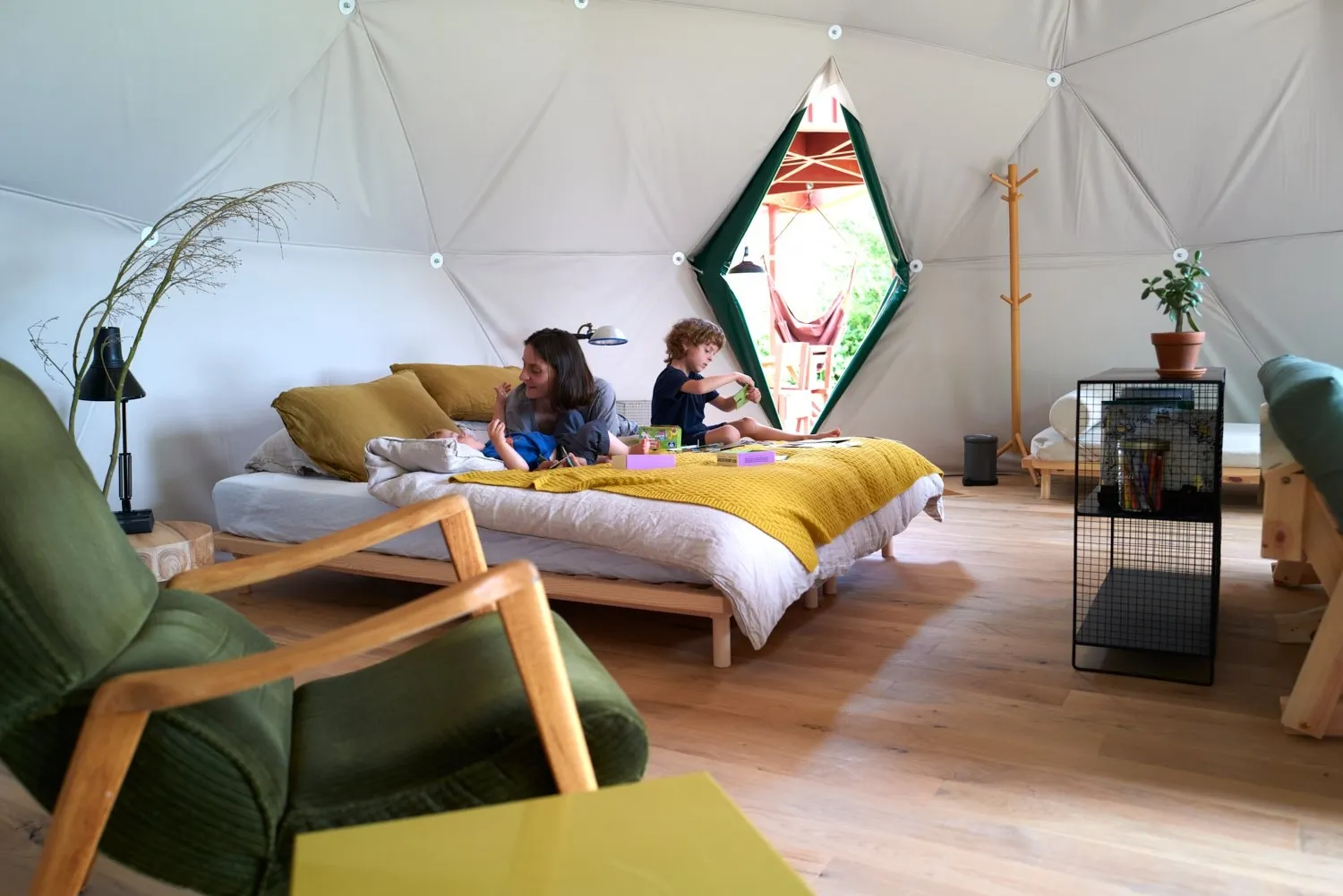 a woman with kids laying on bed inside of geodesic dome