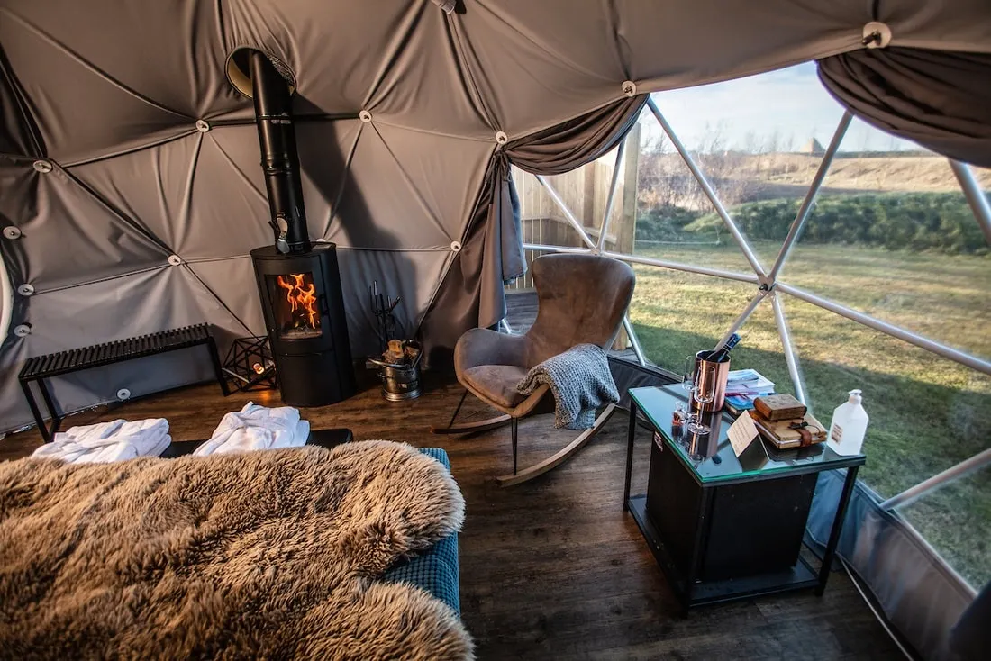 inside of geodesic dome with a bed, an armchair and a stove