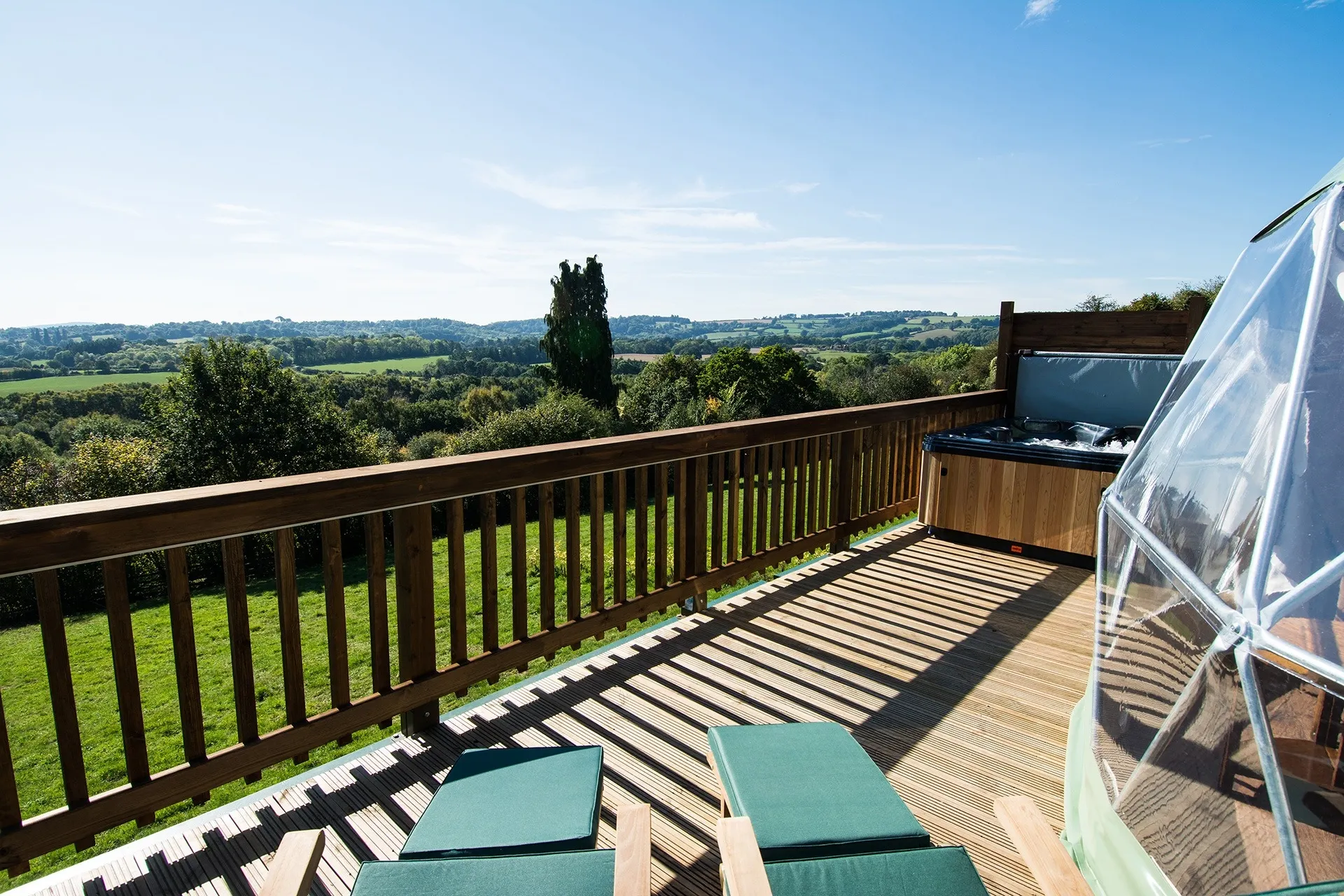 green olive geodesic dome on wooden decking with jacuzzi with a view on fields
