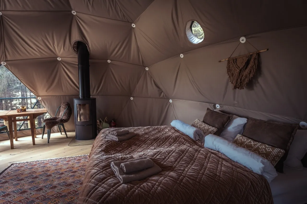 inside of geodesic dome with a stove, a bed and a table with chair