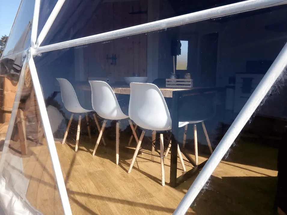 geodesic dome from window side with a view on some chairs and table inside