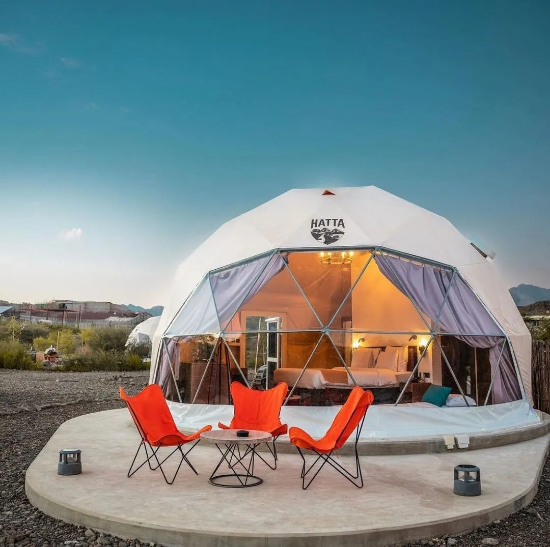 three orange chairs in front of white geodesic dome with logo Hatta