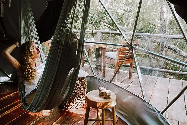inside of the glamping geodesic dome and a woman in a hammock looking through the panoramic bay