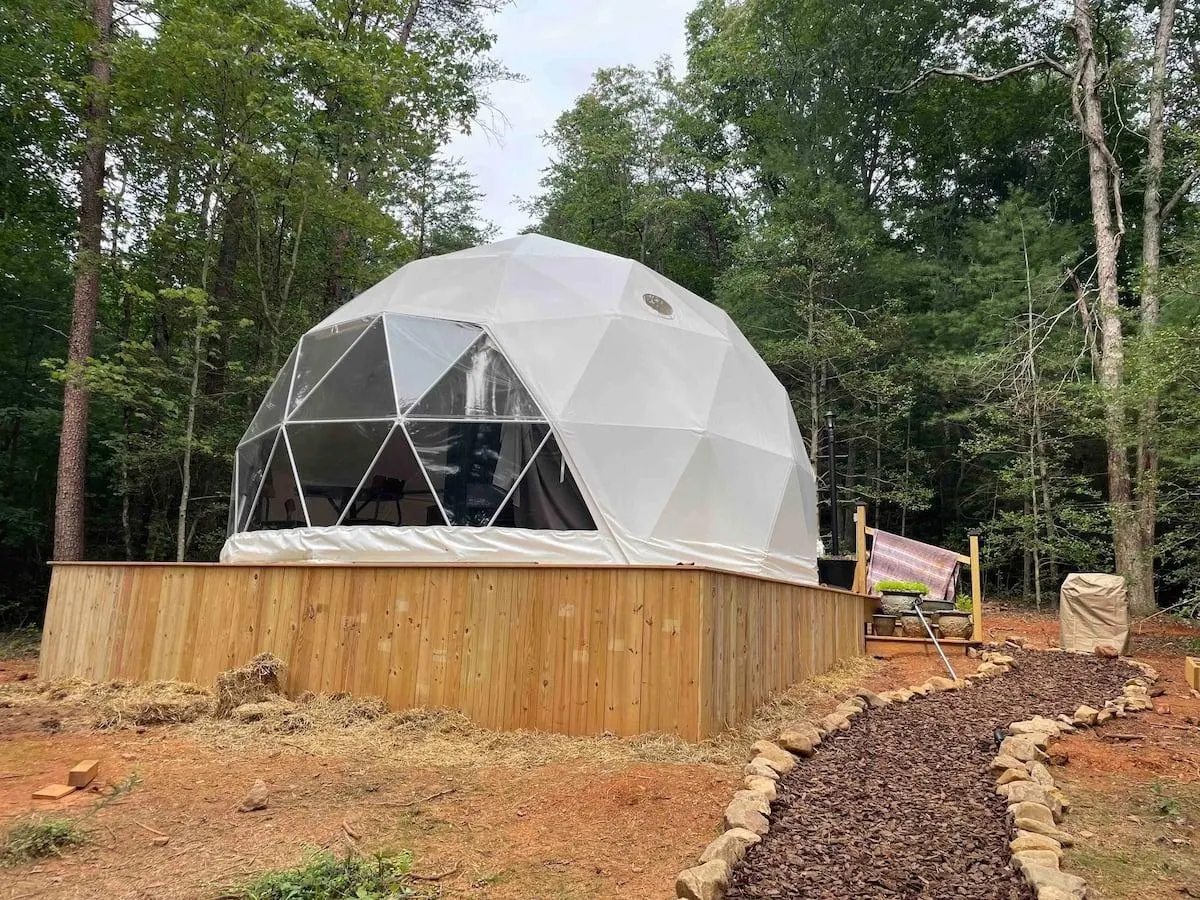 white geodesic dome at wooden platform in forest